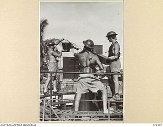 KARKAR ISLAND, NEW GUINEA. 1944-05-18. ABLE SEAMAN A LEECH (1), USES A BUCKET FILLED WITH SEA WATER TO COOL THE BARREL OF A 2 POUNDER GUN ABOARD HMA MOTOR LAUNCH 431. HMA MOTOR LAUNCHES HAVE BEEN ..