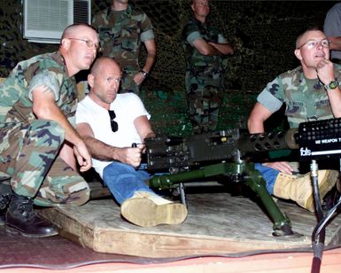 Actor Bruce Willis accompanied by CHIEF Warrant Officers Johnston and Reiltmacher, USMC, (right) fires the M2 .50 Caliber Machine Gun at the Individual Simulated Marksmanship Training (ISMT) facility, Marine Corps Base Hawaii, Kaneohe Bay, for his upcoming movie about Navy SEALS