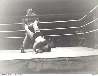 MADANG, NEW GUINEA. 1944-09-16. SERGEANT BERNE TAMBLYN, RAAF (1) AND HIS OPPONENT, TOD HARDWICK, 6TH INFANTRY BATTALION (2) IN AN AWKWARD AND PAINFUL POSITION DURING THEIR BOUT AT THE COMBINED ..