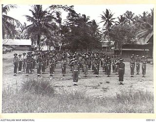 LAE, NEW GUINEA, 1945-12-01. MEMBERS OF LAE BASE SUB AREA WORKSHOP, CORPS OF AUSTRALIAN ELECTRICAL AND MECHANICAL ENGINEERS, PRESENT ARMS DURING A PARADE HELD ON THE OCCASION OF THE THIRD ..
