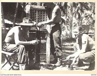 AITAPE AREA, NEW GUINEA, 1944-11-23. SIGNALLERS AT HQ 6 DIVISION AT WORK ON A TERMINAL BOARD. THE BOARD, THE NERVE CENTRE AT DIV HQ, CARRIES ALL INCOMING LINES. IDENTIFIED PERSONNEL ARE:- CORPORAL ..