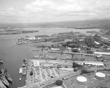 An aerial view of the Naval Supply Center, the Naval Station, Pearl Harbor Submarine Base and various ships moored to piers during Exercise RIMPAC '86