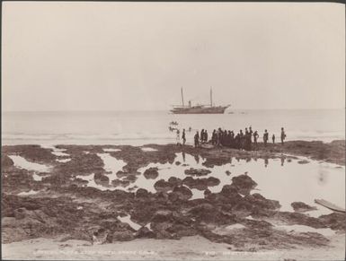 Crowd gathered around a boat at the landing place of Te Motu, Santa Cruz Islands, 1906 / J.W. Beattie