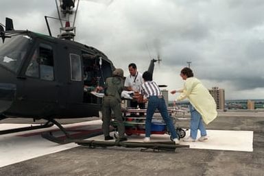 Members of the 68th Medical Detachment at Hickam Air Force Base and Kuakini Hospital Emergency staff help move an overdose victim out of a UH-1H Iroquois helicopter to a waiting emergency elevator at the hospital