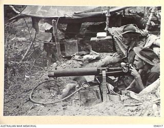 WEWAK AREA, NEW GUINEA, 1945-07-14. A VICKERS MEDIUM MACHINE-GUN PROVIDING COVERING FIRE AS A COMPANY, 2/8 INFANTRY BATTALION, WITH B COMPANY IN SUPPORT, PREPARES FOR THEIR FINAL DASH FOR THE TOP ..