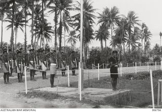 Bare footed guards of the Royal Papuan Constabulary raising the colours at the RAN War Criminal Compound at an RAN shore base. Work on this RAN base commenced in August 1948. It was commissioned as ..