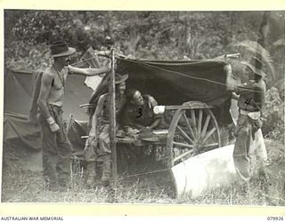 DAGUA, NEW GUINEA. 1945-03-25. MEMBERS OF THE 2/2 INFANTRY BATTALION STANDING BESIDE A "DOOVER" (SHELTER) BUILT ON THE FRAME OF A JAPANESE TRAILER ON THE AIRSTRAIP. IDENTIFIED PERSONNEL ARE:- ..