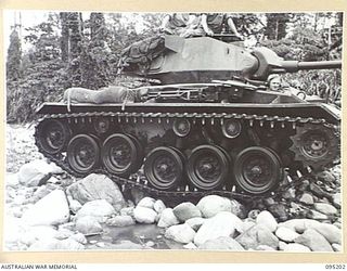 TOROKINA, BOUGAINVILLE, 1945-08-14. AN M24 LIGHT TANK SHOWING ATTITUDE OF SUSPENSION AND TRACKS UNDER STRESS DURING BOULDER CROSSING IN A RIVER BED. SUCH TESTS WERE INCLUDED IN THE ACTIVITIES OF ..