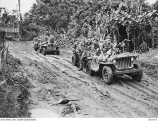 BOUGAINVILLE. 1945-07-18. TROOPS OF 58/59 INFANTRY BATTALION, LOADED INTO JEEPS AND TRAILERS MOVING ALONG THE MUDDY BUIN ROAD EAST OF THE OGORATA RIVER. THE TROOPS ARE ON THEIR WAY TO A BEACH REST ..