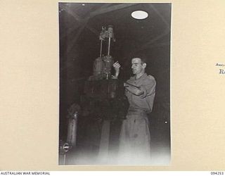 PALMALMAL PLANTATION, NEW BRITAIN. 1945-07-21. WARRANT OFFICER 2 J.E. FRANZINI, 1 INFANTRY TROOPS WORKSHOP, IN THE PROCESS OF RE-BORING THE ENGINE OF A JEEP FOR USE IN RECONDITIONED VEHICLES