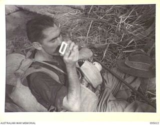 GWALIP, NEW GUINEA, 1945-08-05. PTE C.F. CUNNINGHAM, 2/7 INFANTRY BATTALION, WITH CLOTHES SODDEN WITH SWEAT AND HEAVY PACK AS A PILLOW, TAKES A SHORT SPELL FOR A SMOKE DURING A PATROL INTO ENEMY ..