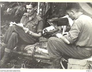 MALIN, NEW GUINEA. 1945-01-25. VX67732 CORPORAL J.G. SAW (1) AND VX6700 SERGEANT G.H. LEWIS, ORDERLY ROOM SERGEANT (2) OPERATING THE UNIT OPEN- AIR ORDERLY ROOM OF THE 2/8TH INFANTRY BATTALION. ..