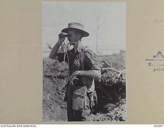 WEWAK POINT, NEW GUINEA, 1945-05-12. LT-COL G.S. COX, COMMANDING OFFICER 2/4 INFANTRY BATTALION, SURVEYING THE COUNTRYSIDE AROUND BATTALION HQ THROUGH BINOCULARS