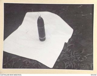 CHABAI/SORAKEN AREA, BOUGAINVILLE, 1945-06-20. A CAPTURED IMPROVISED MINE, WHICH CAN BE ELECTRICALLY DETONATED, MADE FROM A JAPANESE 75 MM SHELL. IT IS PHOTOGRAPHED OUTSIDE II INFANTRY BRIGADE ..