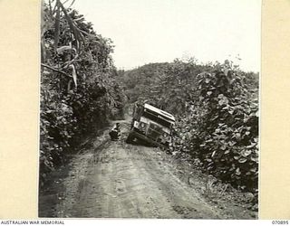 WAU - LAE ROAD, NEW GUINEA, 1944-02-26. THE ROAD SURFACE AFTER RAIN. THE THREE TON VEHICLE FROM THE 2/9TH FIELD COMPANY, ROYAL AUSTRALIAN ENGINEERS HAS SLID TO THE EDGE OF THE ROADWAY WHICH HAD ..