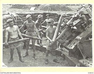 PORT MORESBY, PAPUA. 1942-07. STRIPPED TO THE WAIST, THESE SUN-TANNED GUNNERS OF THE A.I.F. KEEP UP THE SUPPLY OF SHELLS DURING AN ENEMY AIR RAID IN NEW GUINEA. THESE TROOPS WERE IN THE MIDDLE EAST