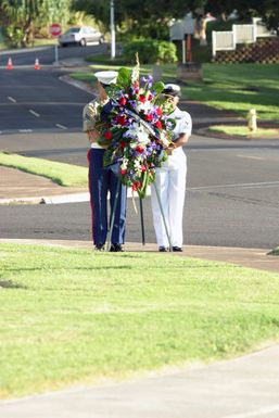 Two wreath bearers one US Marine Corps (USMC) Marine and one US Navy (USN) Sailor march with a memorial wreath to the Kilpper Memorial during the Kaneohe Klipper Ceremony, on December 7, 2004, at Marine Corps Base Hawaii (MCBH) Kaneohe Bay