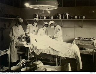 Port Moresby, New Guinea. 1944-05-29. Captain Dunstone, Medical Officer, 128th Australian General Hospital, with his staff in the operating theatre performing surgery on Private M. J. Cronin. Left ..