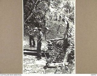 DUMPU, NEW GUINEA, 1943-10-08. TROOPS OF THE 2/6TH AUSTRALIAN FIELD COMPANY, ROYAL AUSTRALIAN ENGINEERS, CONSTRUCTING A CAUSEWAY AND BRIDGE OVER A STEEP SIDED CREEK IN THE RAMU VALLEY. SHOWN ARE:- ..