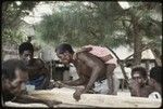 Manus: men building a canoe, small child on one man's back, Pere village