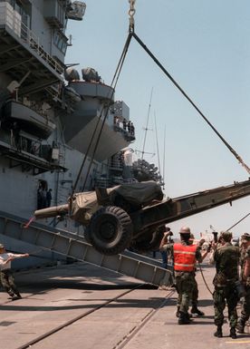 Marines load a Howitzer aboard the amphibious assault ship USS GUAM (LPH 9) during Exercise SOLID SHIELD '87