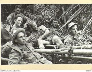 1943-08-03. NEW GUINEA. MUBO CAMPAIGN. AMERICAN TROOPS RESTING DURING THE ARDUOUS TASK OF DRAGGING PARTS OF AMERICAN ARTILLERY PIECES OVER A MOUNTAIN 2747 FEET HIGH TO BOMBARD JAP POSITIONS NEAR ..