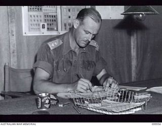 RABAUL, NEW BRITAIN, 1946-03-30. LIEUTENANT E.J. GILROY, OFFICER COMMANDING, MOBILE CINEMA HQ, AUSTRALIAN ARMY AMENITIES SERVICE PREPARING FUTURE PROGRAMMES