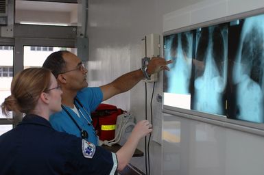 US Navy (USN) Navy Hospital Corpsman Third Class (HM3) Mary A. Rhudy (foreground) and USN Lieutenant (LT) Junius Dural, discuss a patient's X-rays in the Emergency Room at Agana Naval Air Station (NAS), Guam