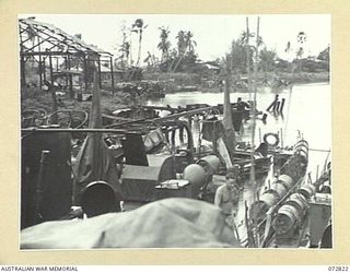 MADANG, NEW GUINEA, 1944-04-30. A CROWDED SCENE AT WHARVES IN THE HARBOUR DURING THE EARLY MORNING AS LANDING CRAFT AND MOTOR LAUNCHES MAINTAIN THE FOOD SUPPLIES TO TROOPS. MOTOR TRANSPORT IS ..