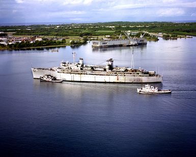 A port beam view of the repair ship USS JASON (AR 8) as harbor tugs approach to assist the vessel into port