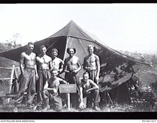 ORO BAY, NEW GUINEA. 1943. MEMBERS OF NO. 4 GUN CREW, 5TH HEAVY ANTI-AIRCRAFT BATTERY, 2/2ND ANTI-AIRCRAFT REGIMENT, OUTSIDE THEIR TENT SIGNPOSTED 'RUCKER'S HILL' INCLUDING MARSHALL, TOMASETTI, ..