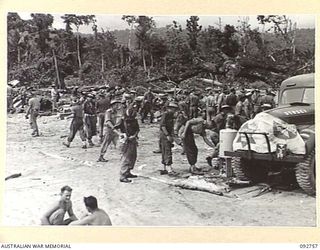 WEWAK AREA, NEW GUINEA. 1945-05-31. TROOPS OF 111 AND 119 SUPPLY DEPOT PLATOONS RECEIVING REFRESHMENTS FROM A SALVATION ARMY RED SHIELD TRUCK AT THE BEACH-HEAD AFTER DISEMBARKING FROM SS SUVA, THE ..