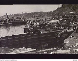 LAE, NEW GUINEA, 1943-10-12. AN AMPHIBIOUS TRUCK (KNOWN AS A DUKW), OF THE AUSTRALIAN MOVEMENT CONTROL, LEAVES THE WATER NEAR THE DOCK KNOWN AS THE DUKW WAY. NOTE DUKW WAS CODED BY GENERAL MOTORS: ..