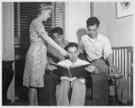 Mrs. Eldon Burke, director of the Brooklyn Hostel for Japanese Americans, shows an album of clippings to Robert Kazahaya, Kohay