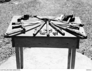 HOPOI DISTRICT, NEW GUINEA, 1943-10-30. COLLECTION OF JAPANESE WEAPONS HANDED IN TO NX155085 CAPTAIN R.G. ORMSBY OF THE AUSTRALIAN AND NEW GUINEA ADMINISTRATIVE UNIT ON HIS VISIT TO THE DISTRICT, ..