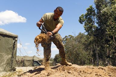 US Marine Corps (USMC) Lance Corporal (LCPL) Rivera, Headquarters and Service Company, 2nd Battalion, 3rd Marine Regiment (2/3), Marine Corps Base Hawaii (MCBH), Hawaii (HI), uses an E-Tool (USMC Improved Entrenching Tool) to rearrange dirt as he builds a terrain model at Exercise CROCODILE 2003