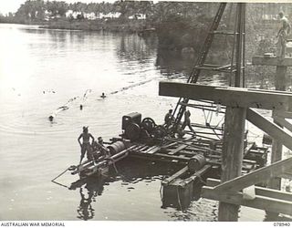 JACQUINOT BAY, NEW BRITAIN. 1945-02-09. NATIVES FLOATING LARGE LOGS DOWN A STREAM. THESE LOGS ARE TO BE USED AS STRINGERS ON THE NEW HIGH LEVEL BRIDGE OVER THE KALUMALAGI RIVER WHICH IS BEING BUILT ..