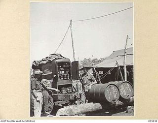 CAPE WOM, WEWAK AREA, NEW GUINEA. 1945-08-30. WARRANT OFFICER 2 D.E. REES (1), WARRANT OFFICER 2 A. HARDINGHAM (2) AND LIEUTENANT L.J. HARTMAN (3), LOOKING OVER GENERATOR PANEL AND MOTOR AT 2/4 ..