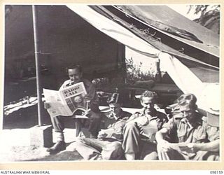 WEWAK POINT, NEW GUINEA. 1945-10-23. THE STAFF OF RADIO STATION 9AJ, 1 BROADCASTING STATION, AUSTRALIAN ARMY AMENITIES SERVICE, READING THEIR MAIL. SERGEANT E. PARRANT, WHO DID NOT RECEIVE ANY, ..