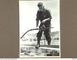 BEBEI, NEW GUINEA. 1943-12-21. NX23791 SERGEANT J. M. LANE OF THE 2/6TH AUSTRALIAN FIELD COMPANY, ROYAL AUSTRALIAN ENGINEERS, OPERATING A PNEUMATIC WOOD DRILL ON BEAMS TO BE USED ON THE ..