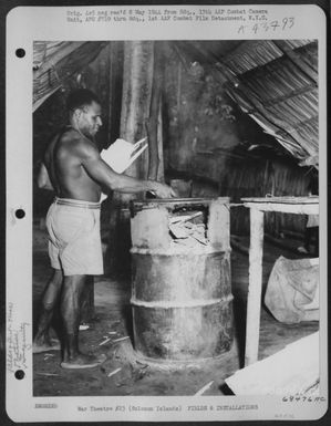 After The Morning Clean-Up Somewhere In The Solomon Islands, A Native Fils The Incinerator (A Discarded Fuel Drum) With The Accumulated Debris. April 1944. (U.S. Air Force Number 68476AC)