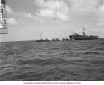 Portside of LSM with picket boats and native outrigger canoe tied to ramp, 1947