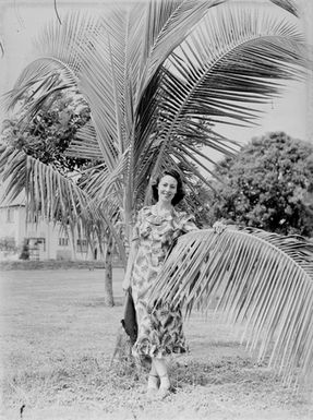 [Portrait of a woman standing next to a palm tree]