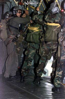 US Marine GUNNERY Sergeant Elder (2nd from left), Platoon Sergeant, 2nd Platoon, Company A, 5th Reconnaissance Battalion, 3rd Marine Division, checks the static lines on the MC1-1C parachutes one last time to ensure safety for his Marines before jumping out of the US Air Force C-141 Starlifter rover the drop zone above the flight line during the Force Reconnaissance Exercises