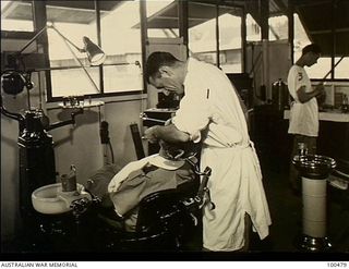 Port Moresby, New Guinea. 1944-05-29. Captain A. E. Johns, Dental Officer, attending to his patient Sister Fletcher, Australian Army Nursing Service (AANS) in the dental surgery at 128th Australian ..