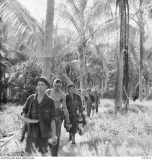 WANIGELA, NEW GUINEA. 1942-10. AMERICAN INFANTRYMEN MARCHING ALONG A NATIVE TRACK IN THE JUNGLE TO GET THEIR "CHOW"