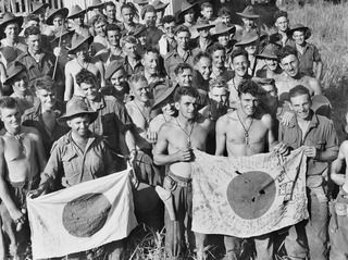 KAIAPIT, NEW GUINEA, 1943-09-22. TROOPS OF THE 2/6TH AUSTRALIAN INDEPENDENT COMPANY DISPLAY CAPTURED JAPANESE FLAGS AFTER THE KAIAPIT ACTION