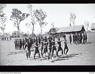 BISIATABU, NEW GUINEA. 1943-07-01. 1ST PAPUAN INFANTRY BATTALION PARADE GROUND WHERE TRAINING COMPANY CAN BE SEEN DRILLING IN SECTIONS. DRILL INSTRUCTOR IS NX3546 SERGEANT A. D. CAHILL