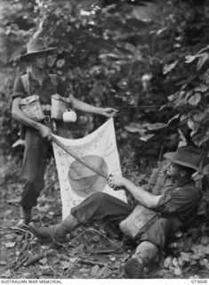 KARKAR, NEW GUINEA. 1944-05-27. NX131536 PRIVATE W.R. CLARKE (1), AND NX156225 LANCE-SERGEANT C.J. JOYCE (2), MEMBERS OF THE 35TH INFANTRY BATTALION, HOLD A JAPANESE FLAG AND SWORD WHICH THEY ..