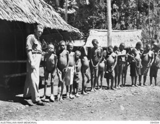 SIPILANGAN, NEW BRITAIN, 1945-07-27. WARRANT OFFICER 2 T. PALFRAMAN WITH A GROUP OF NATIVES WHO ARE AWAITING MEDICAL ATTENTION OUTSIDE THE REGIMENTAL AID POST AT THE AUSTRALIAN NEW GUINEA ..
